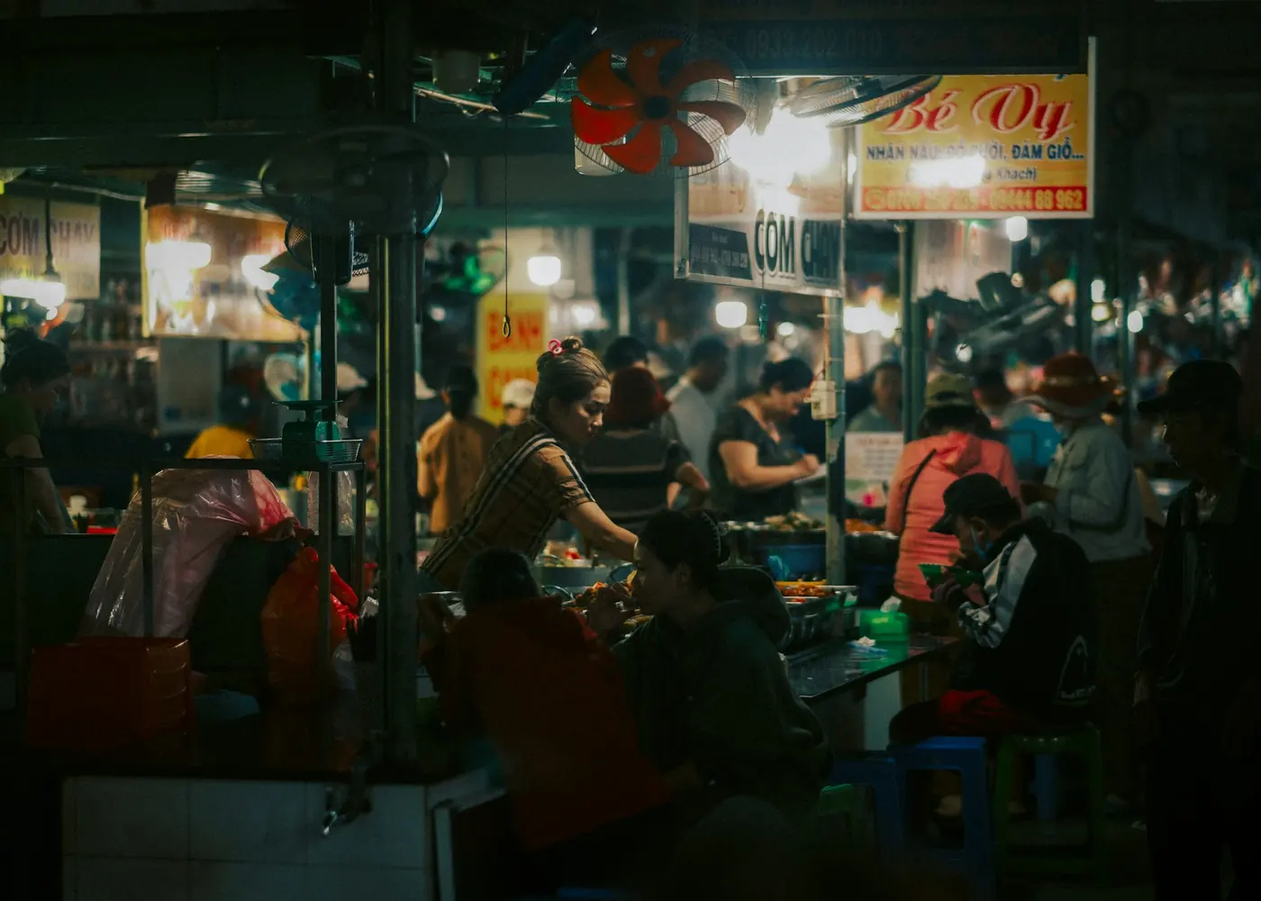 A busy food hall with people eating at long tables