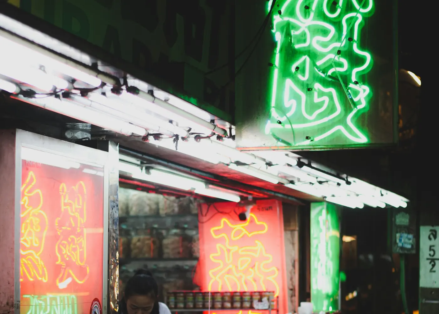 A neon-lit food stall glowing red and green