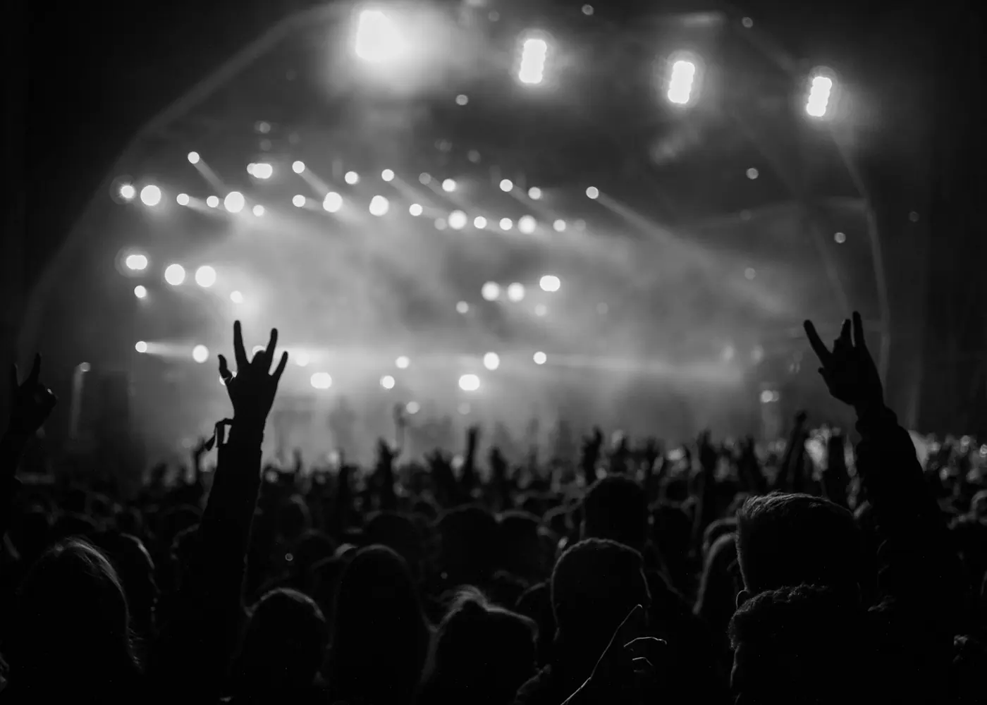 A crowd with raised hands in front of a lit stage