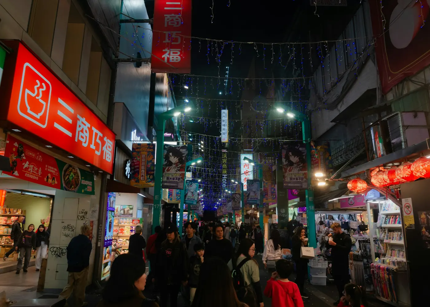 A narrow street lit by lanterns and shop signs